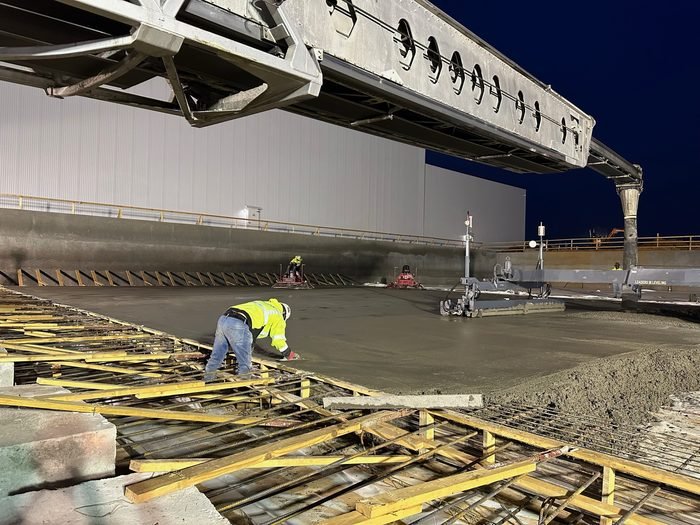 Laser screed placing a large industrial concrete slab at dusk